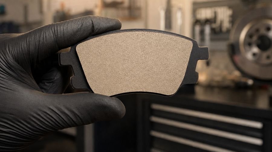 New brake pad held by the edges with clean gloves